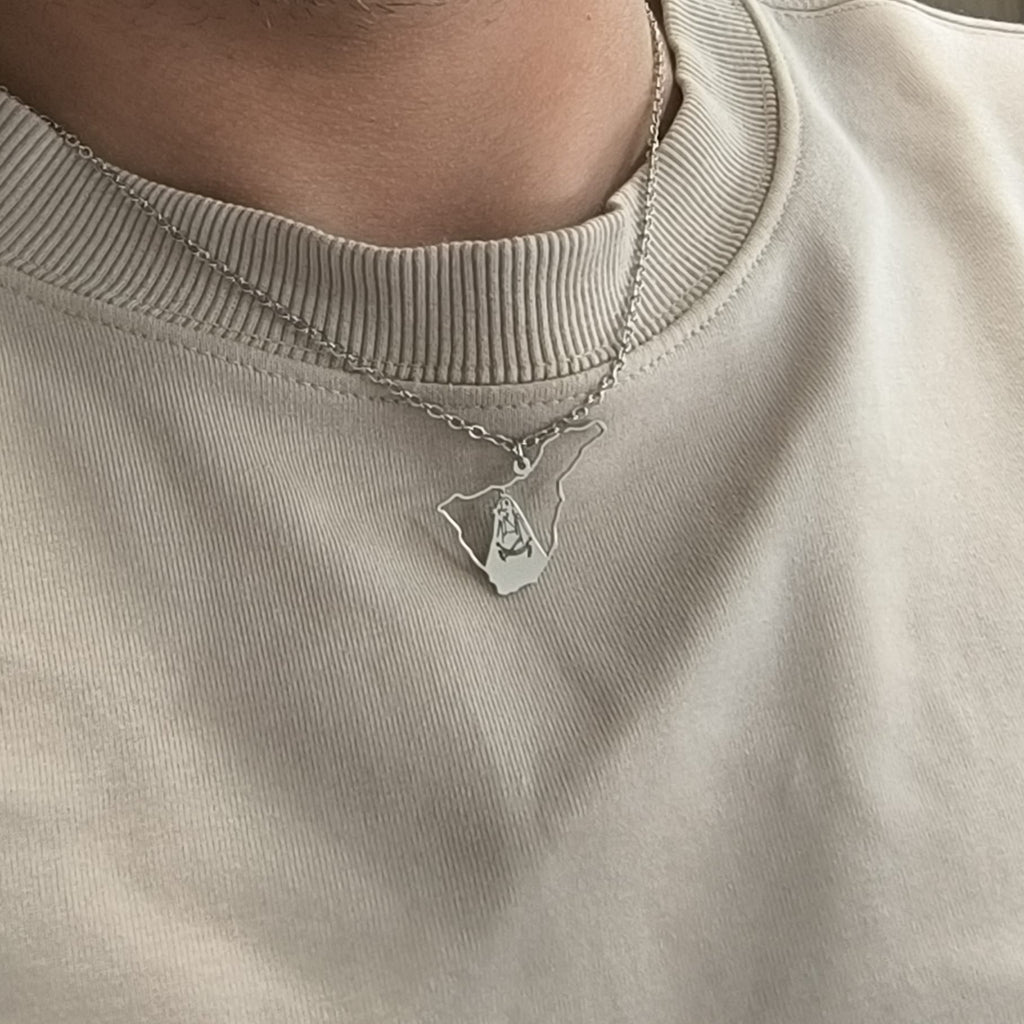 Collar de la Virgen de Candelaria de Tenerife en acabado plateado, llevado sobre una camiseta